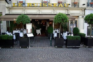 Exterior del restaurante Le Ruisseau, con terraza y estilo arquitectónico europeo clásico.