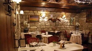 A restaurant with stone walls, wooden beams, and tables set for dining. - Le Ruisseau (Saint-Mandé)