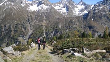 Un sendero de montaña con excursionistas, rodeado de terreno rocoso y picos nevados.