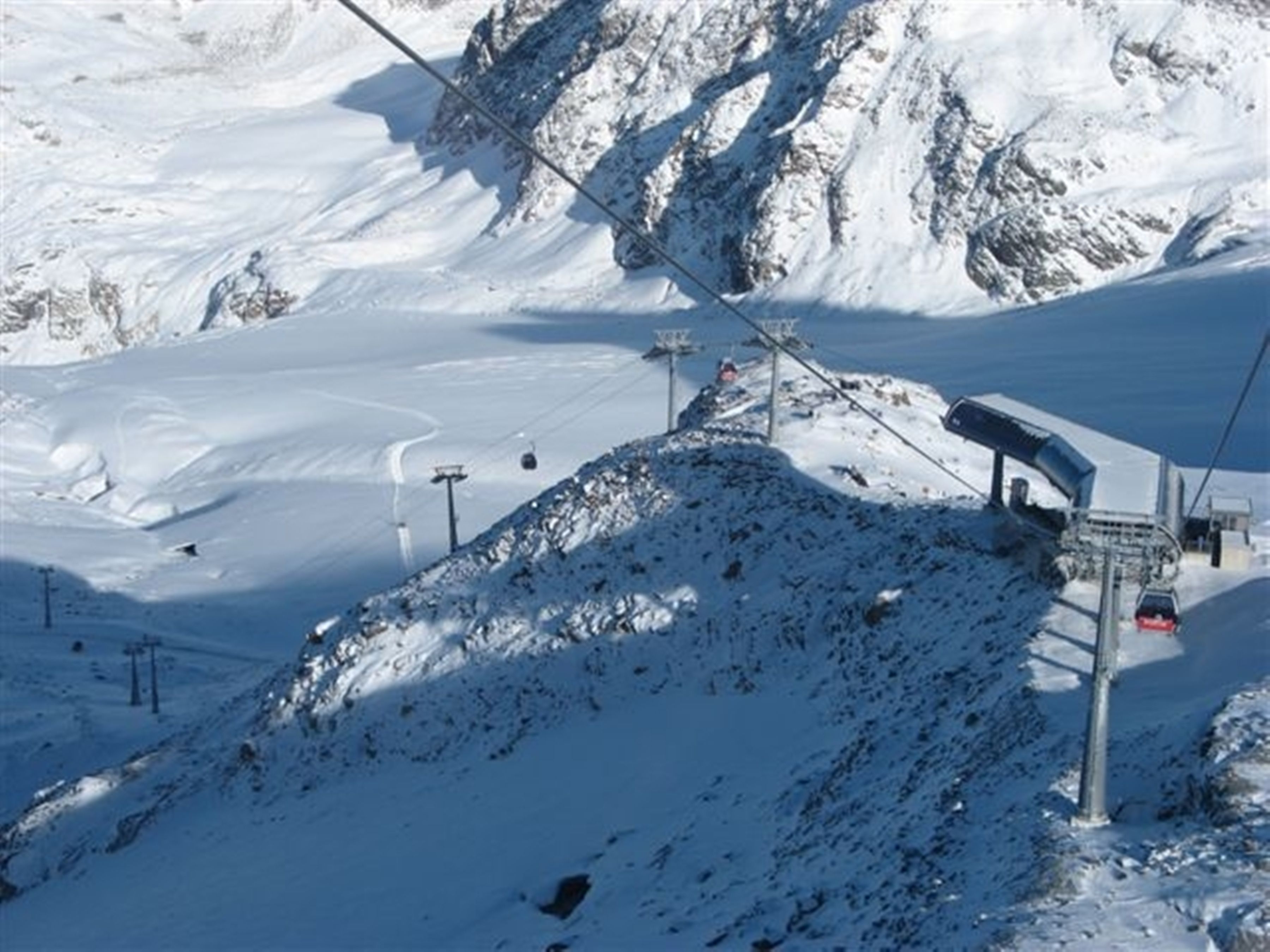 Montaña nevada con telesillas y un asiento elevador.