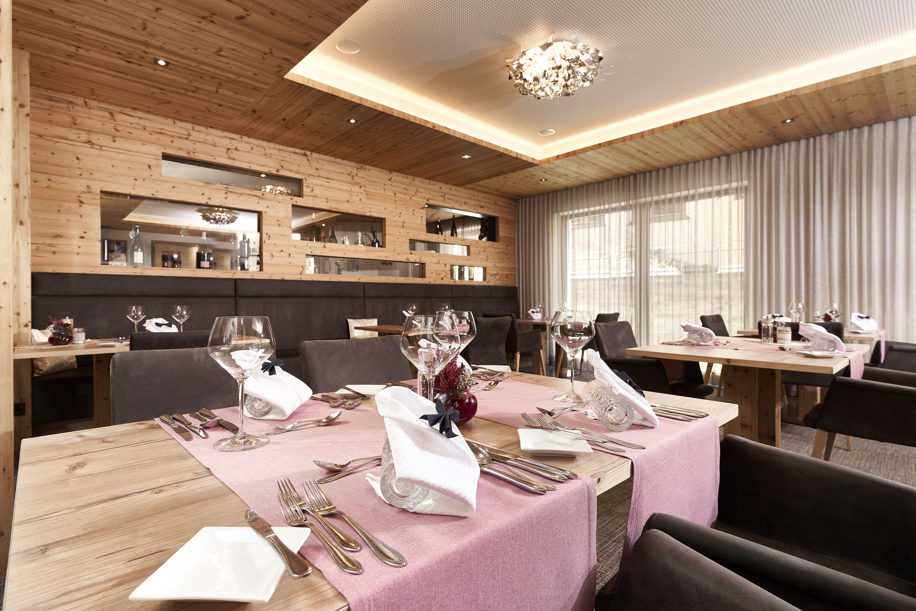 Comedor con paredes de madera, varias mesas dispuestas con manteles blancos y un candelabro.