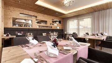 Comedor con paredes de madera, varias mesas dispuestas con manteles blancos y un candelabro.