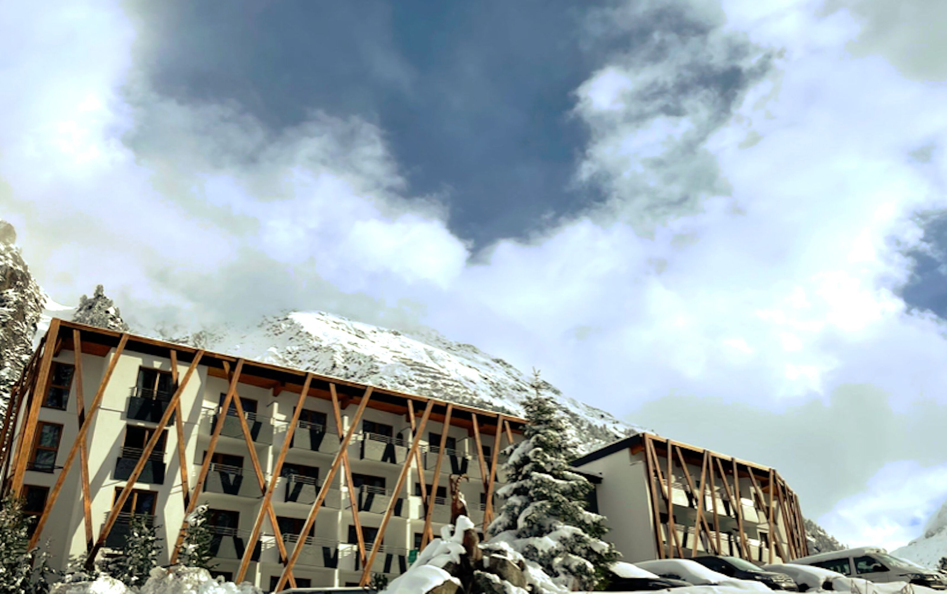 A hotel with a modern architectural design, featuring a prominent wooden framework and a snowy landscape.