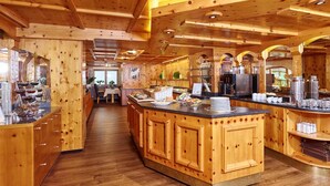 A wooden interior with a central island, wooden cabinets, and a kitchen area with appliances. - Hotel Gundolf  (Sankt Leonhard im Pitztal)