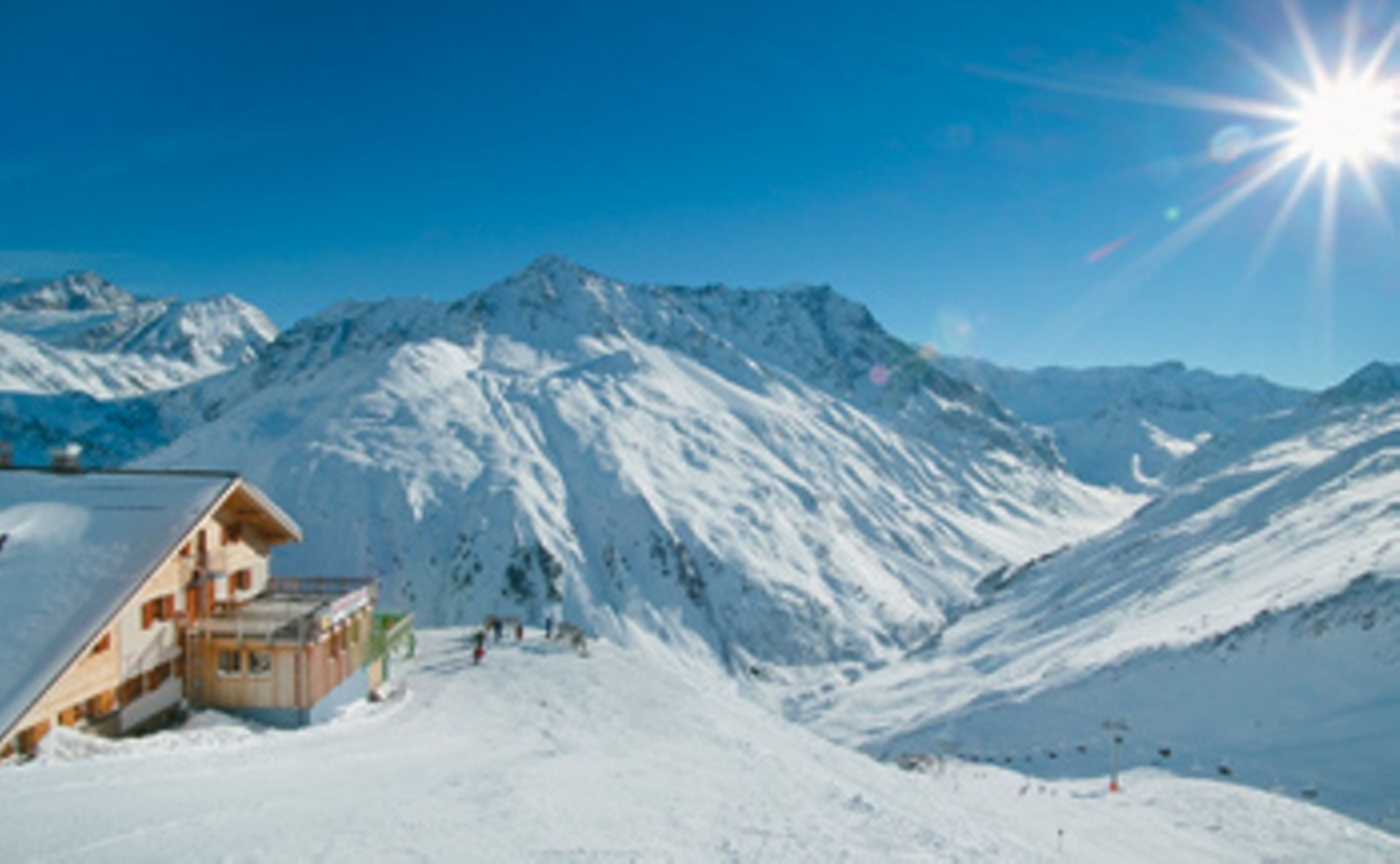 A snow-covered mountain with a wooden building on the left.