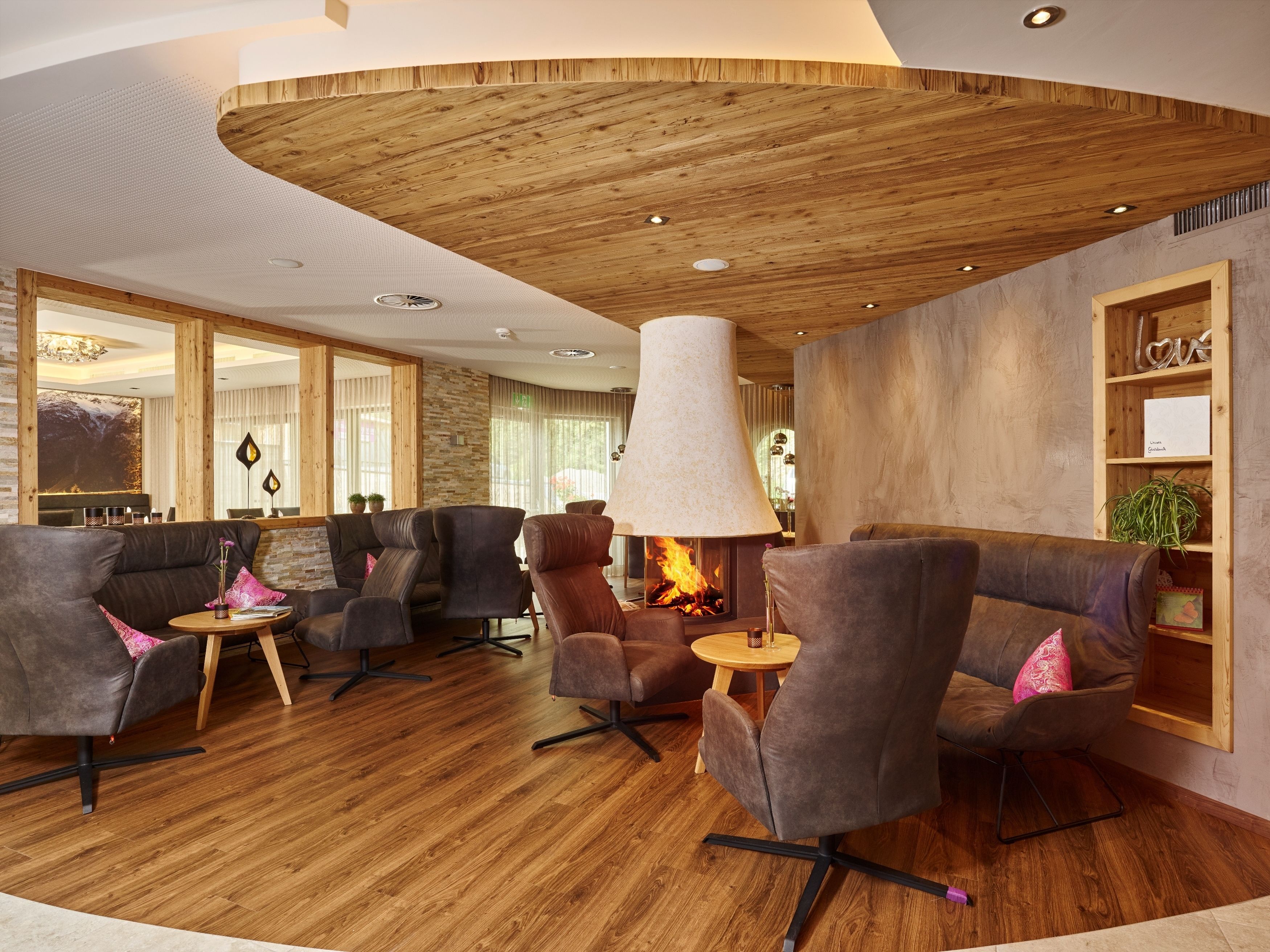 Ein stilvoller Lounge-Bereich mit Ledersofas, Kamin, Holzboden und einer Bücherwand mit Dekorationselementen.