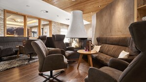 A modern living room with a wooden ceiling, a large lamp, and a sofa with cushions. - Hotel Gundolf  (Sankt Leonhard im Pitztal)