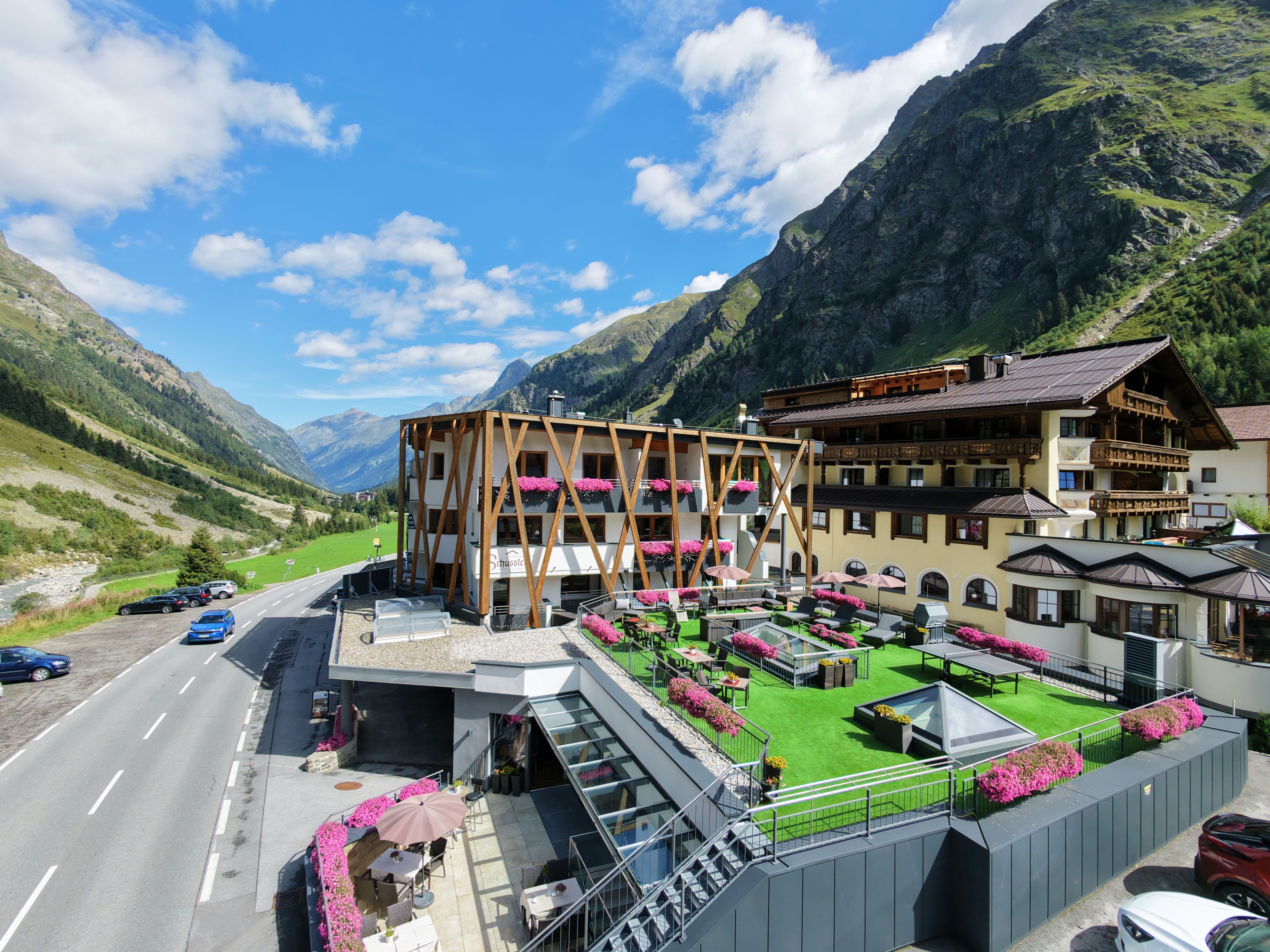 A hotel with a terrace, outdoor seating, and mountain views.
