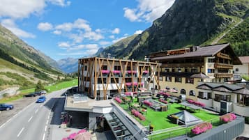 A hotel with a terrace, outdoor seating, and mountain views.