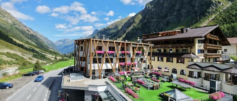 Un hotel con terraza, mobiliario exterior y vistas a la montaña.