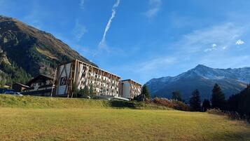 Un hotel con un diseño arquitectónico moderno, ubicado en una zona montañosa con cielo despejado y vistas a picos nevados.