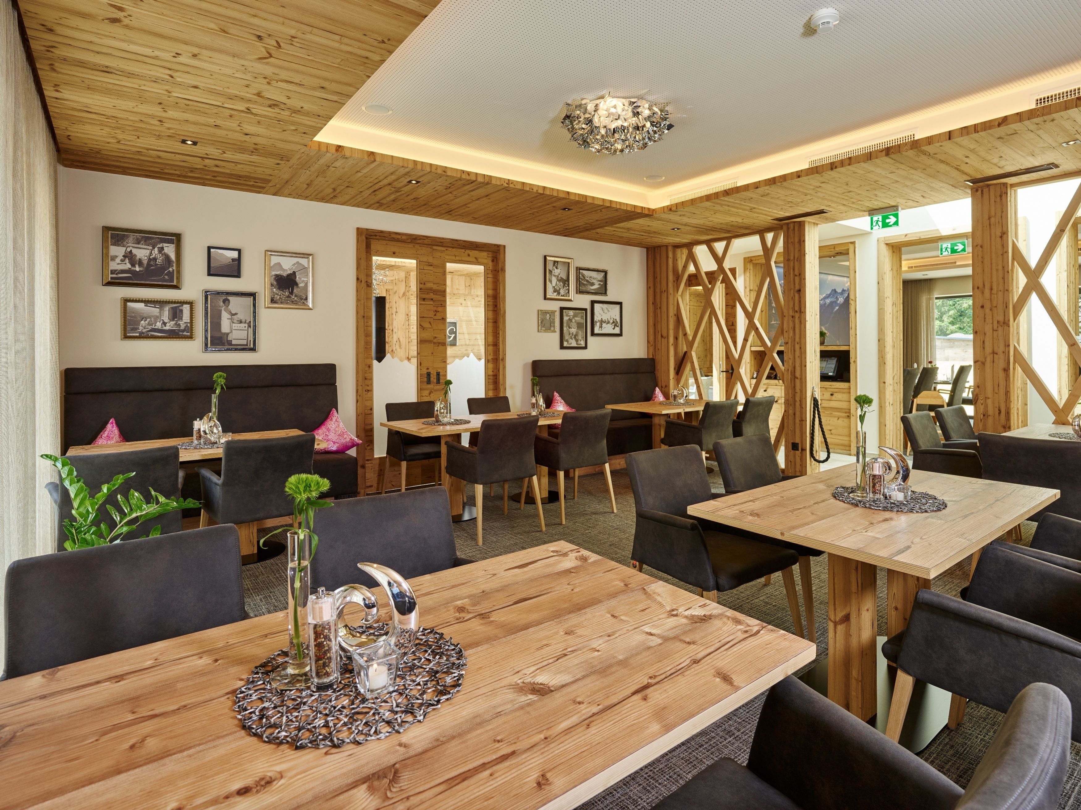 A restaurant with wooden tables and chairs, framed pictures on the walls, and a wooden ceiling.