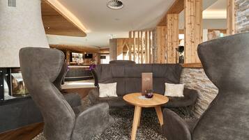 Un interior moderno con un sofá, dos sillones y una pequeña mesa de madera.