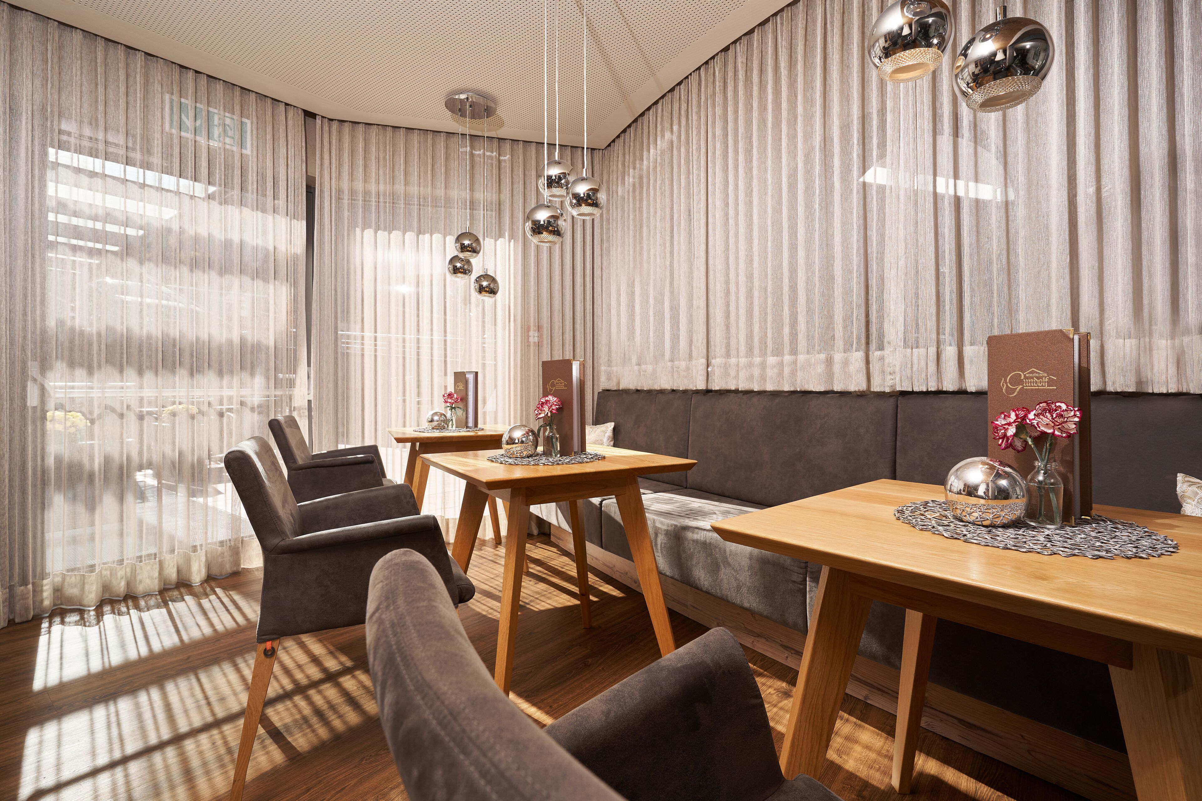 A modern hotel room with a sofa, two armchairs, a wooden table, and a dining table.