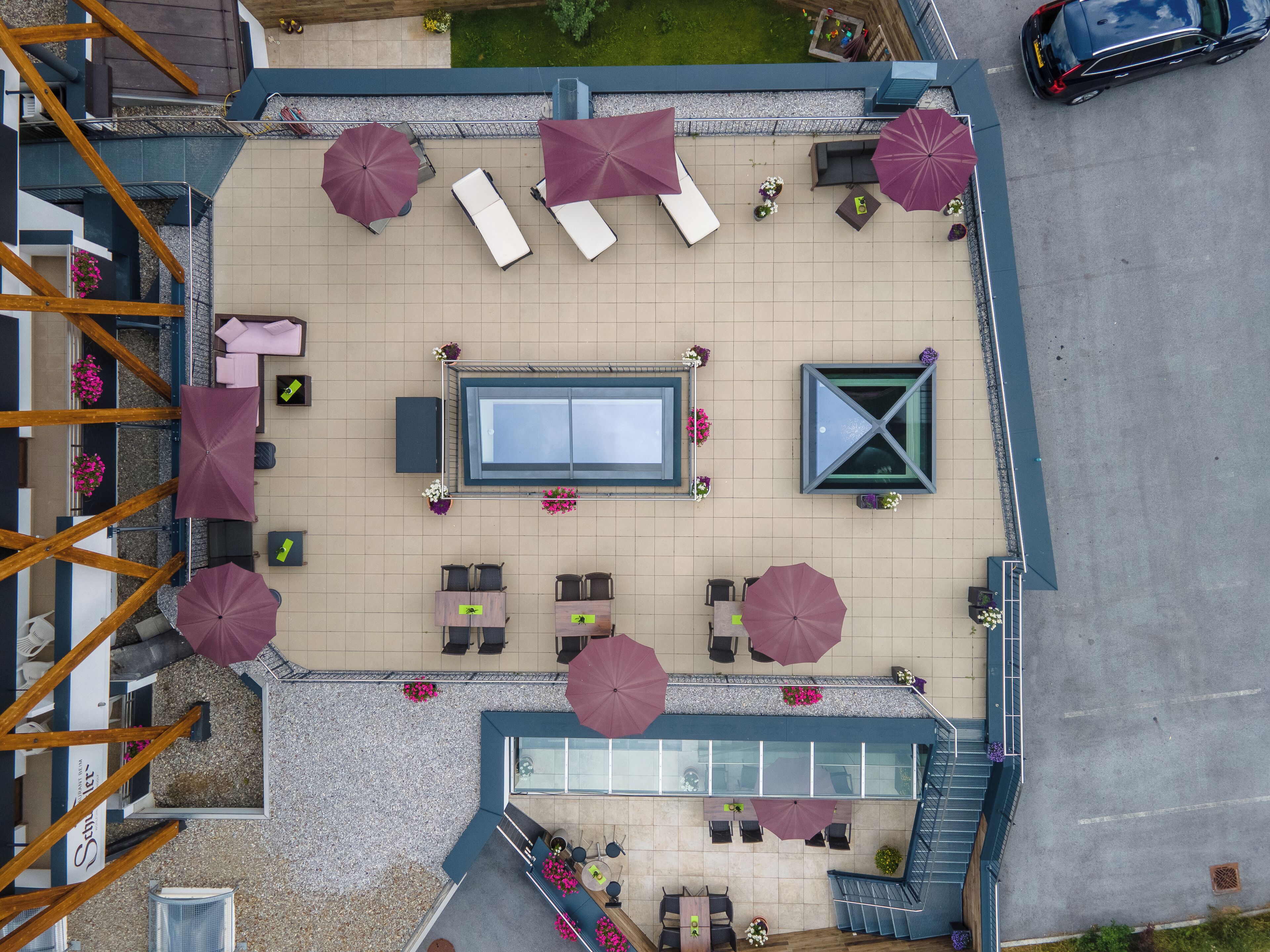 An aerial view of a rooftop terrace with sun loungers, umbrellas, and a pool table.