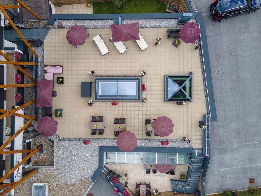 Vista aérea de una terraza en la azotea con tumbonas, sombrillas y una mesa de billar.