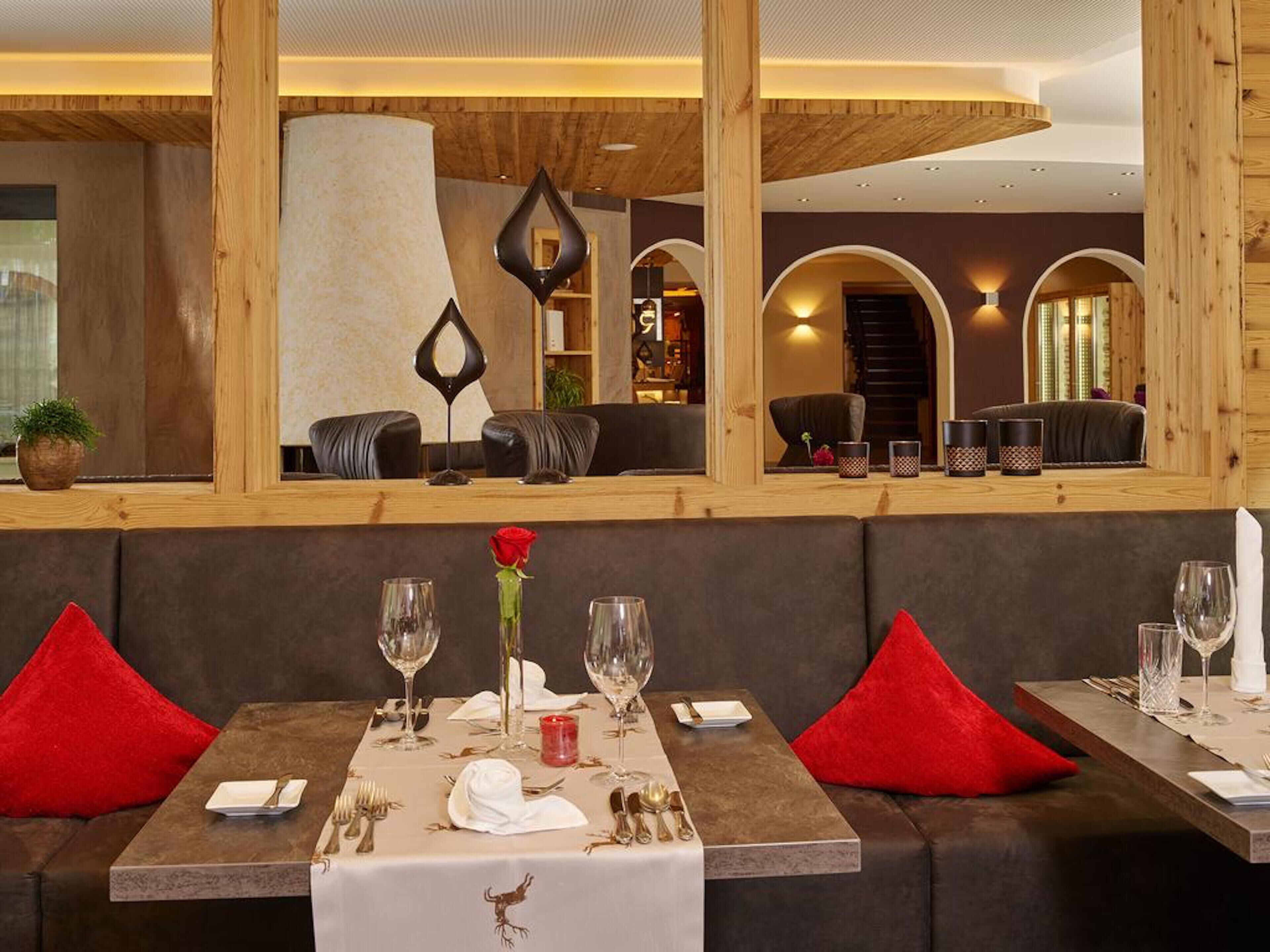 Een restaurant met een modern interieur, met houten balken, comfortabele zithoeken en een centrale kolom.