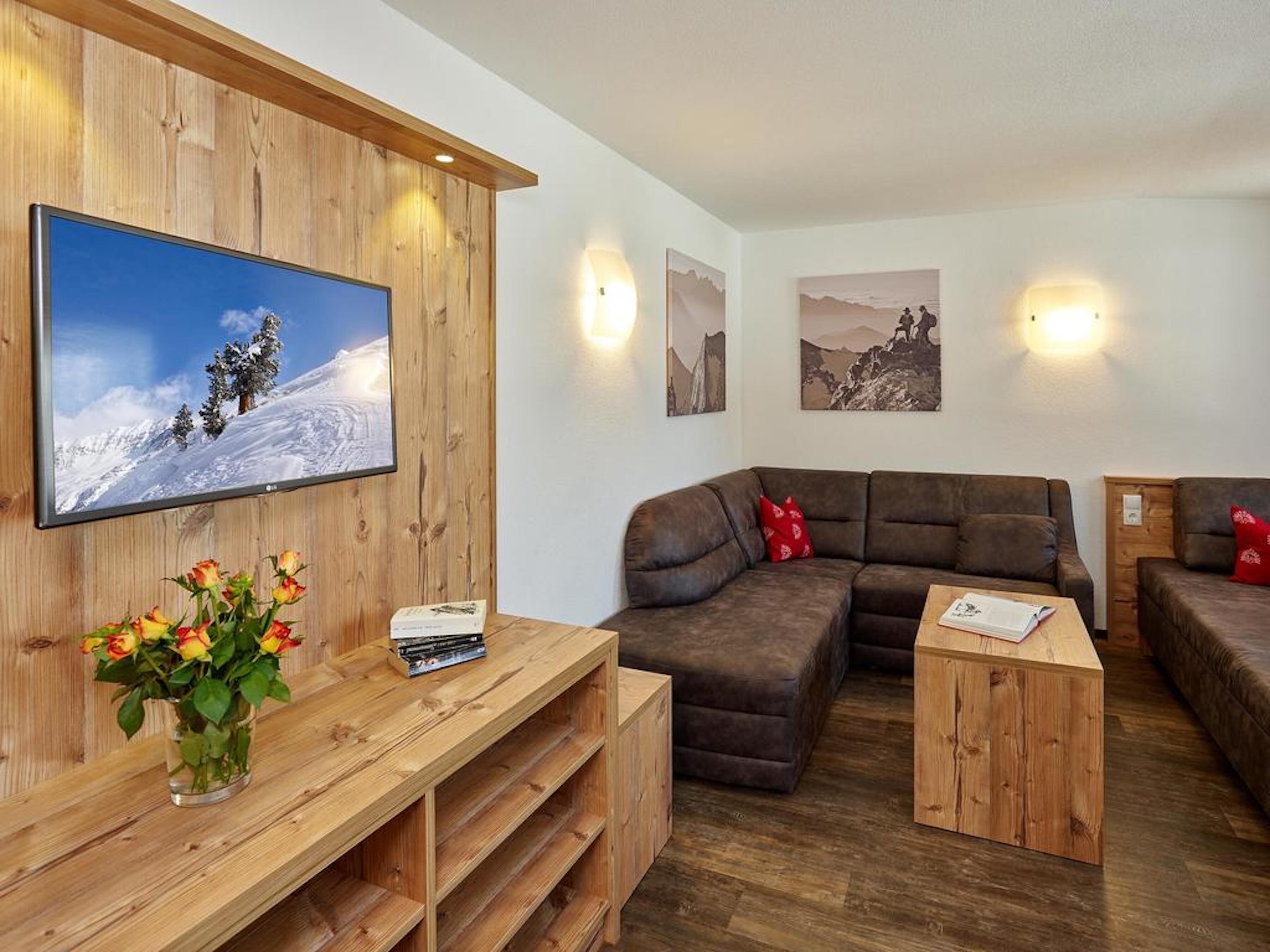 A cozy living area with a wooden TV stand, a brown leather sofa, and a small wooden coffee table.