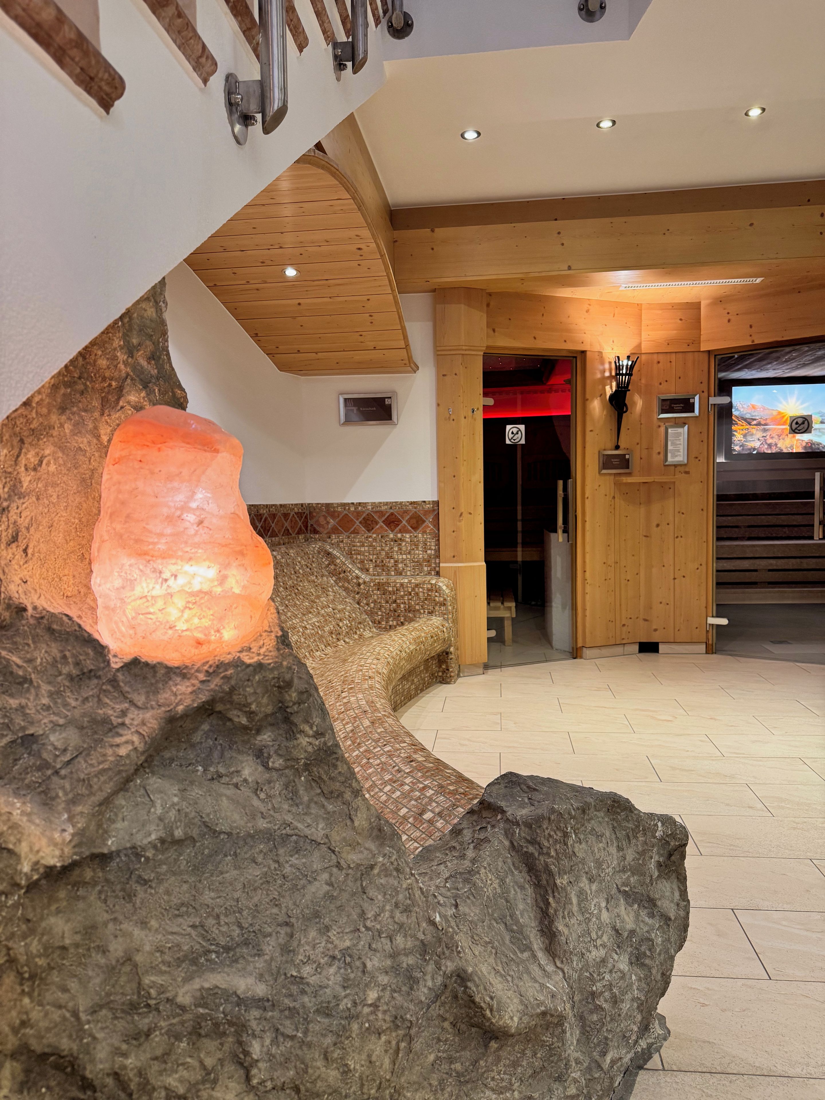 Un vestíbulo de hotel con una gran pieza central de roca, vigas de madera y un mostrador de recepción.