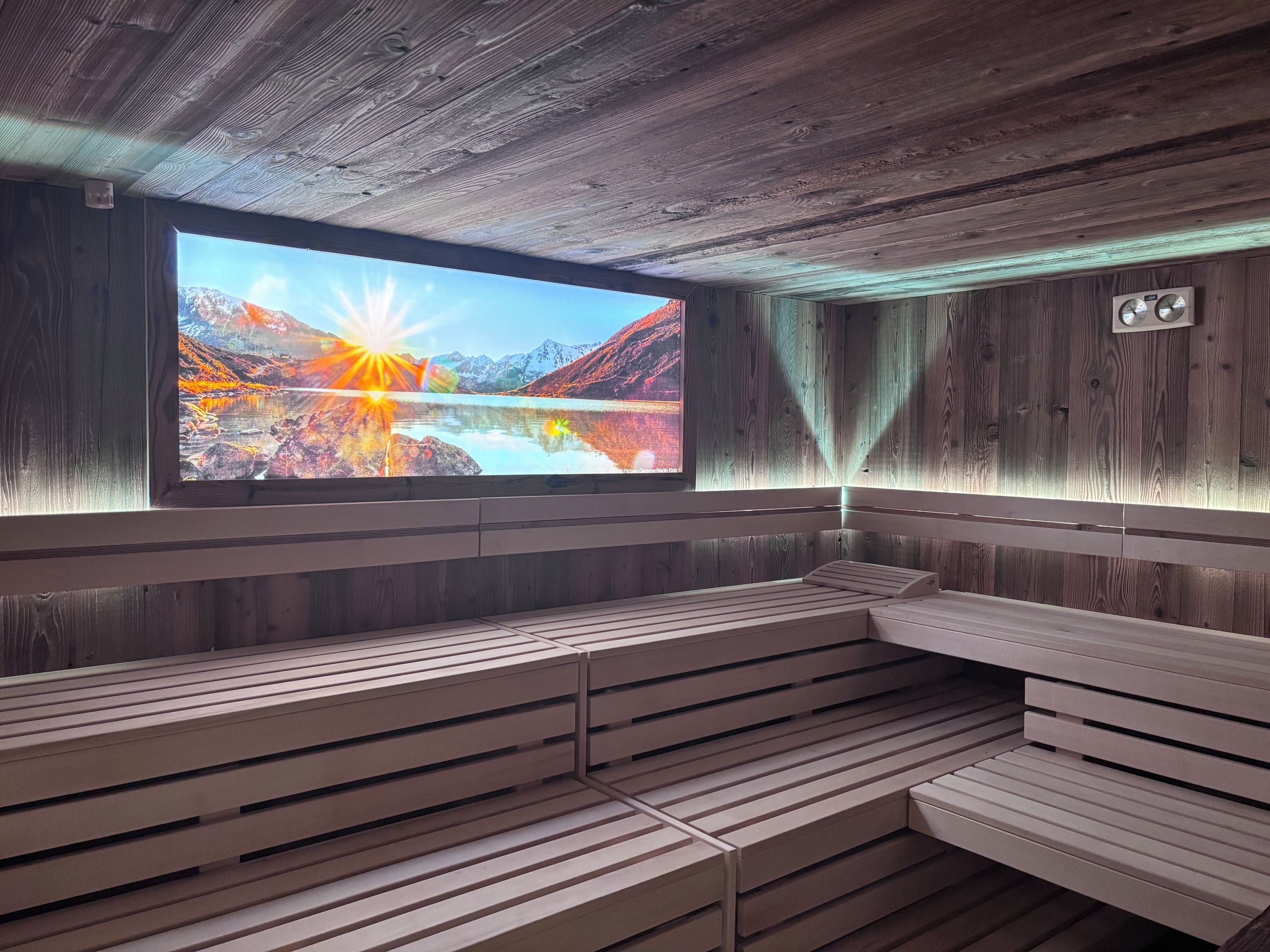 A sauna with wooden benches and a large window displaying a scenic view.