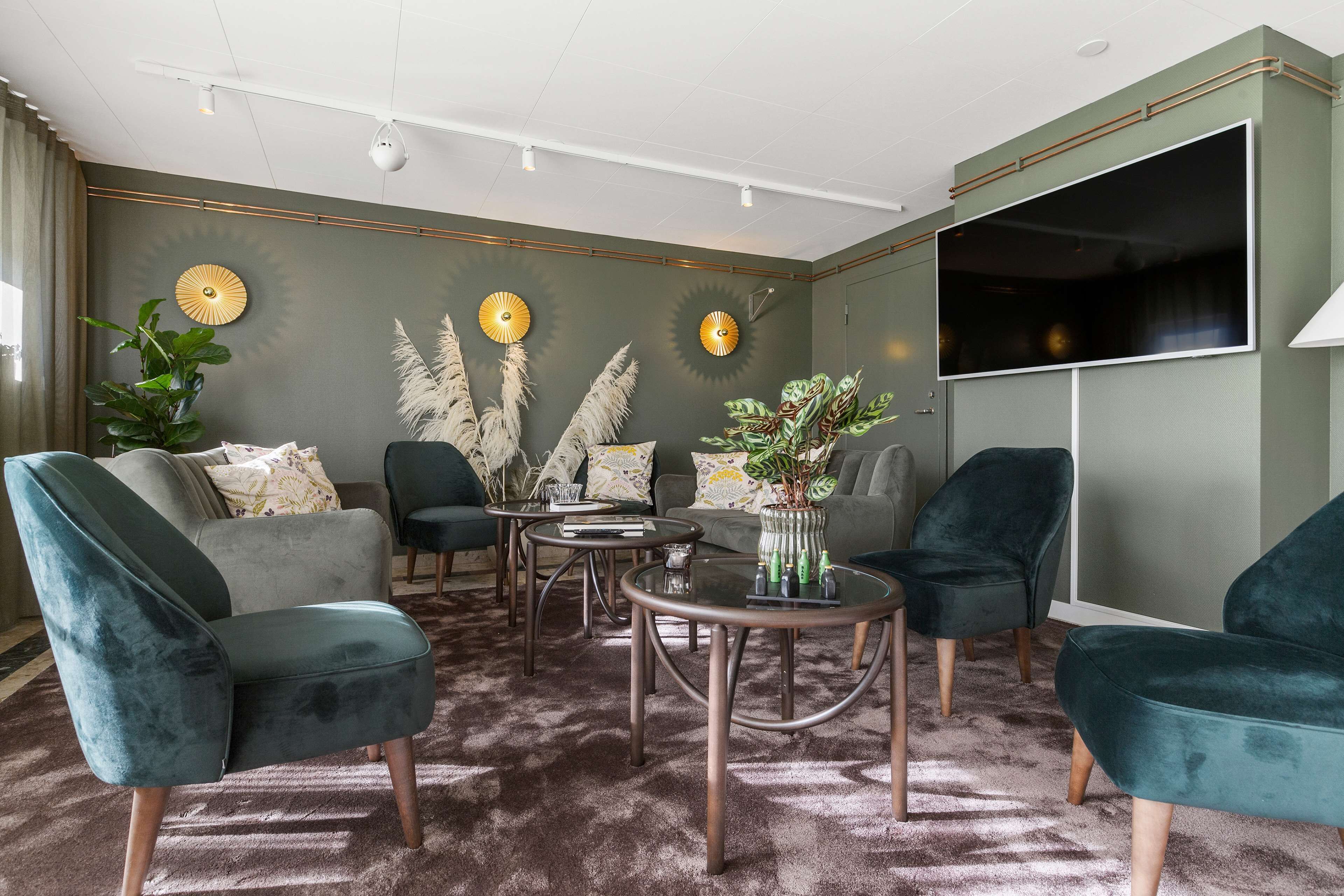 Una sala de estar moderna con un sofá gris, sillones color turquesa, una mesa de centro y plantas decorativas.