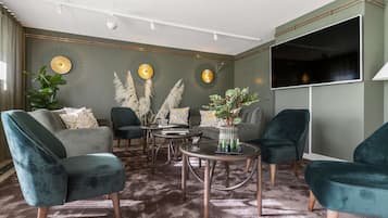 A modern living room with a grey sofa, teal armchairs, a coffee table, and decorative plants.