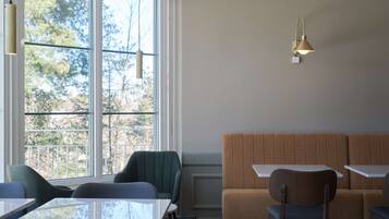 A dining area with a large window, a cushioned bench, and a table with chairs.