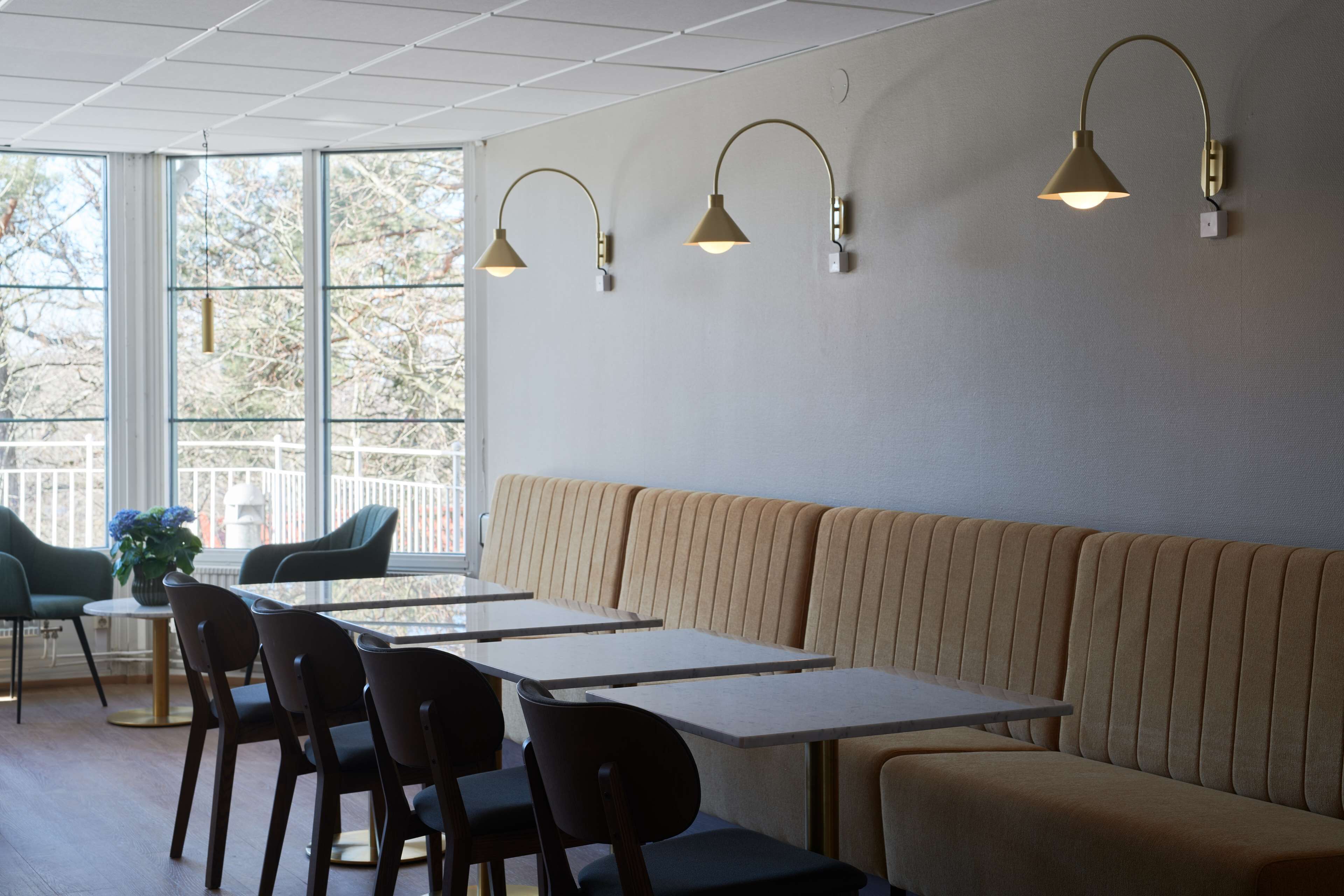 Een moderne eetruimte met een lange bank, meerdere tafels en stoelen.