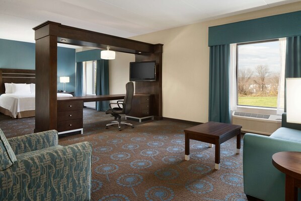 A hotel room with a bed, desk, chair, TV, and large window with a view.