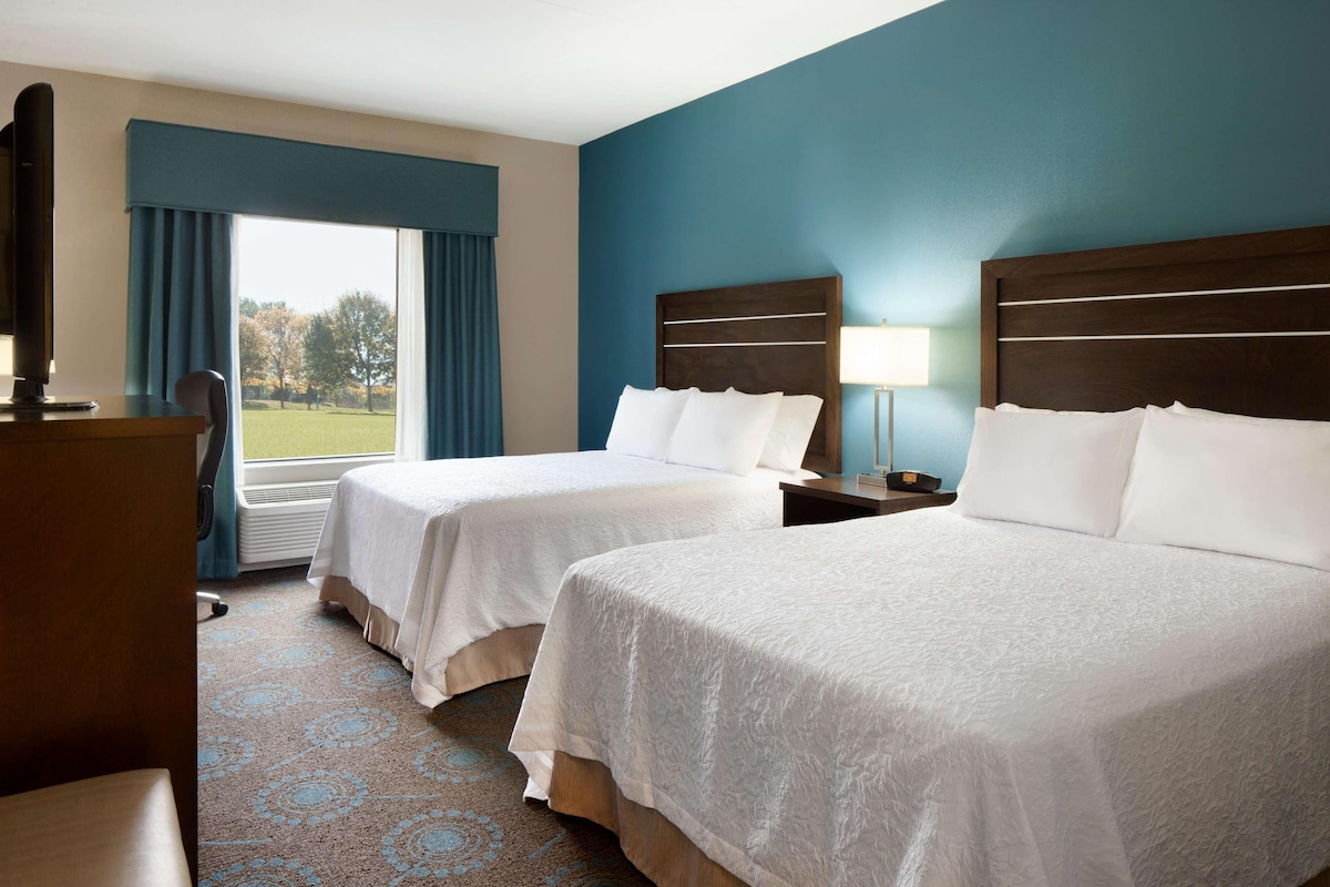 Ein Hotelzimmer mit zwei Betten, einem Schreibtisch und einem Stuhl.