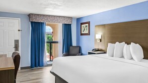 Habitación de hotel con una cama grande, un escritorio, una silla y vistas al exterior.