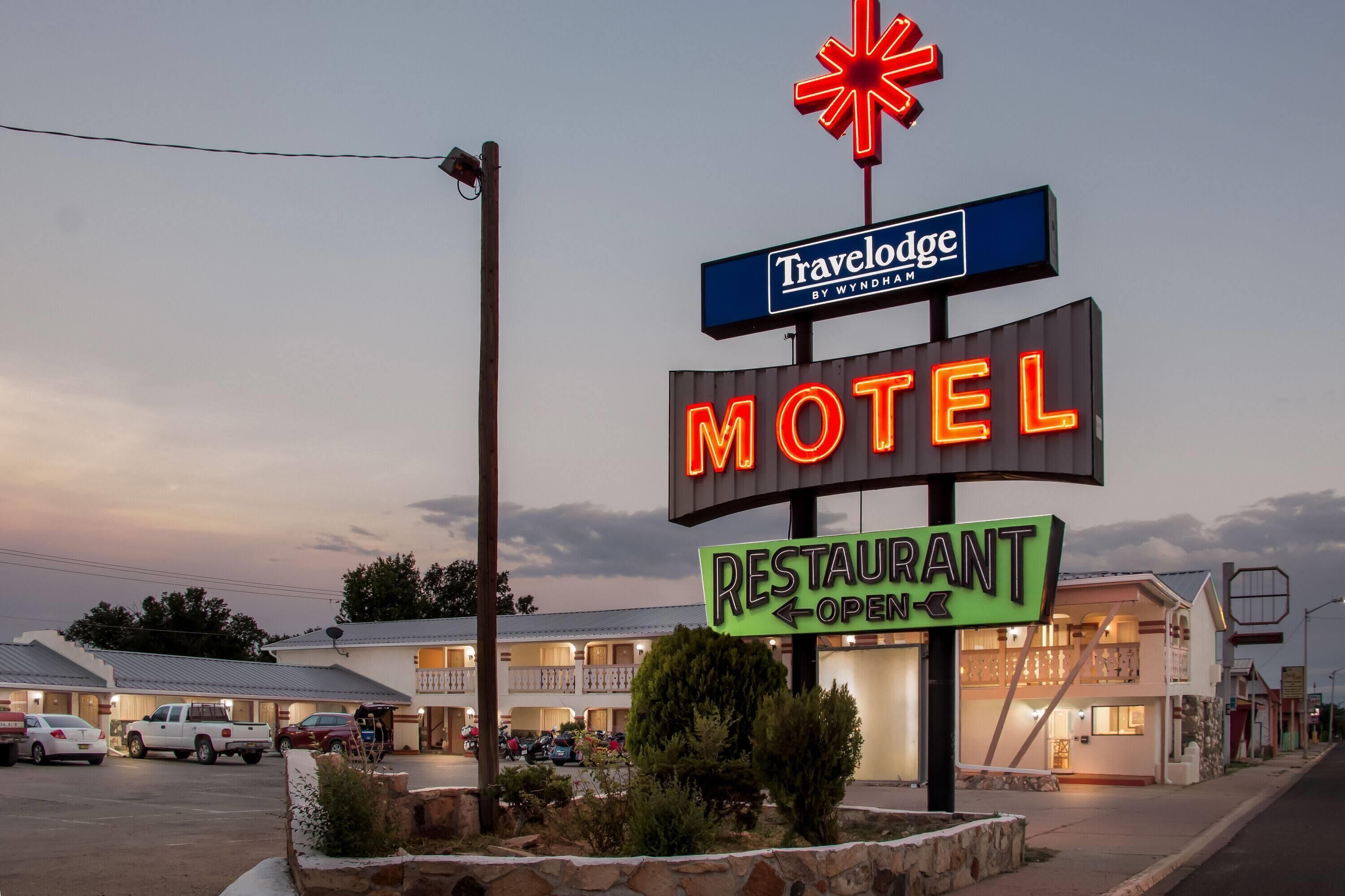 A motel with a neon sign indicating it's a Travelodge by Wyndham, a restaurant, and a motel.