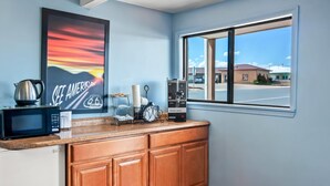 Una cocina con microondas, cafetera y un cuadro en la pared.