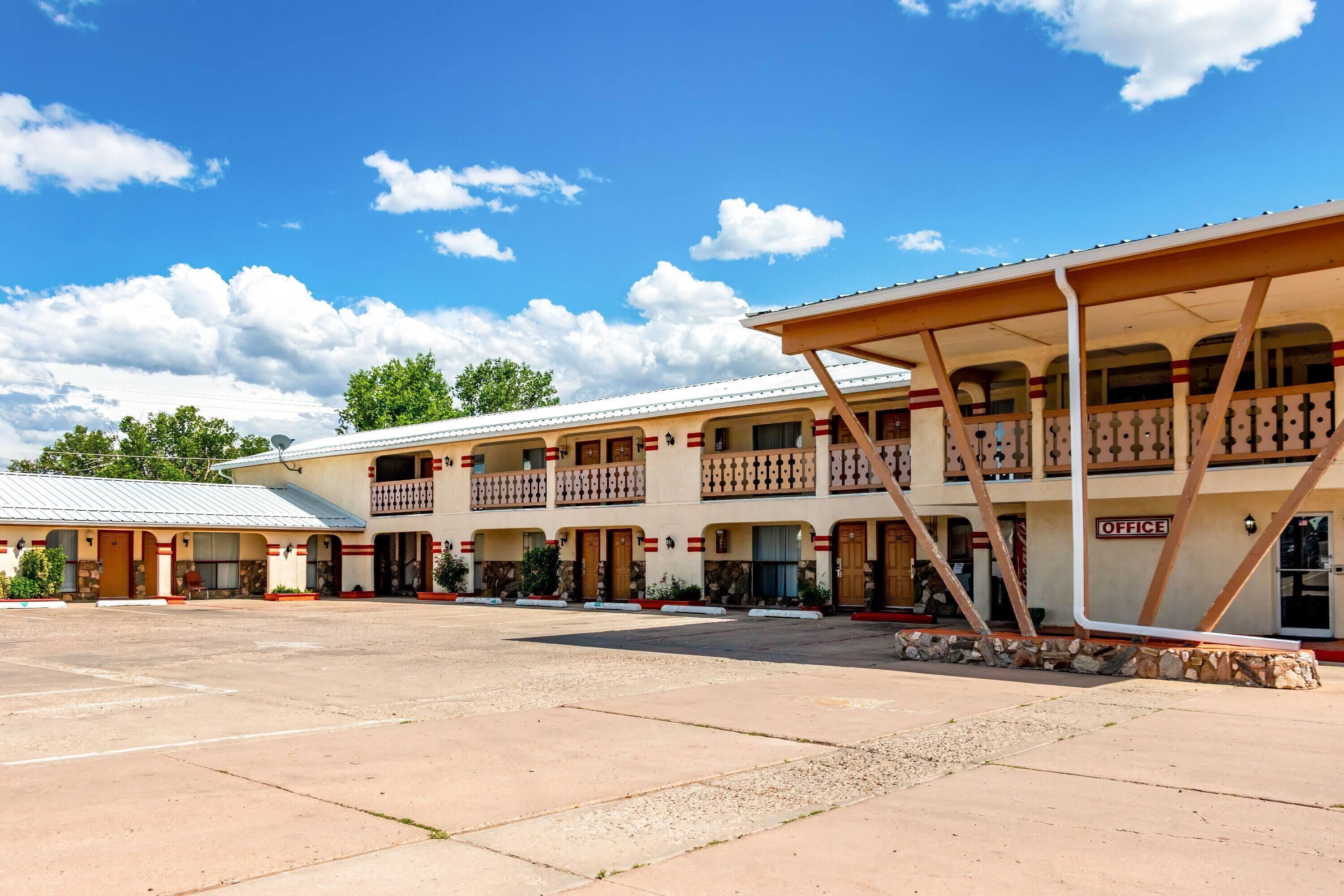 Un motel con un patio central, varios balcones y un edificio de oficinas destacado.