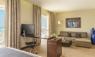 Une chambre d’hôtel avec un lit, un bureau avec un ordinateur, un canapé, une table basse et une vue sur la ville.
