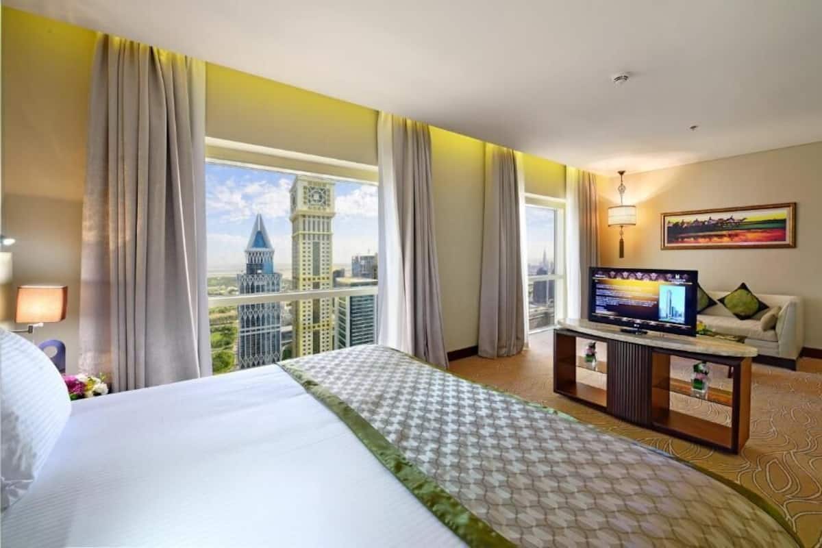 Une chambre d’hôtel avec un grand lit, une télévision et une vue sur le paysage urbain.