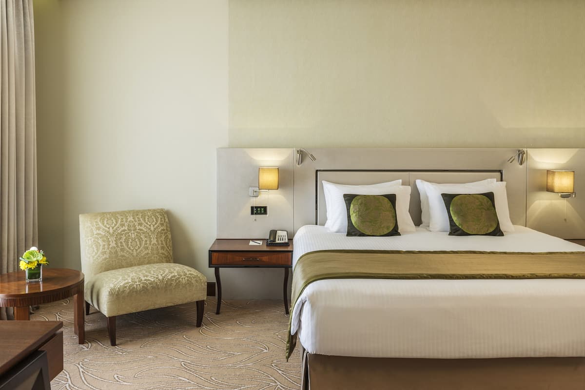 Une chambre d’hôtel avec un lit, une chaise, une table de chevet et une lampe.