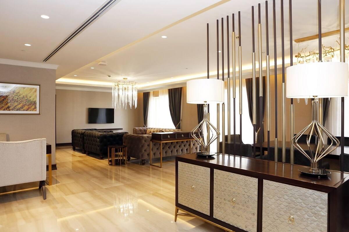 Une chambre d’hôtel moderne dotée d’un canapé confortable, d’un coin repas et d’un grand miroir.