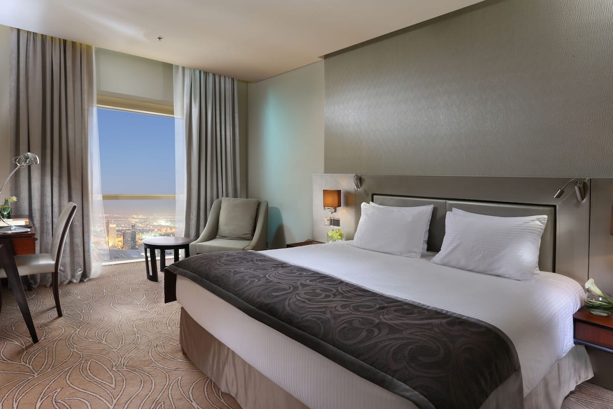 Une chambre d’hôtel avec un grand lit, un bureau, une chaise et une vue sur la ville.