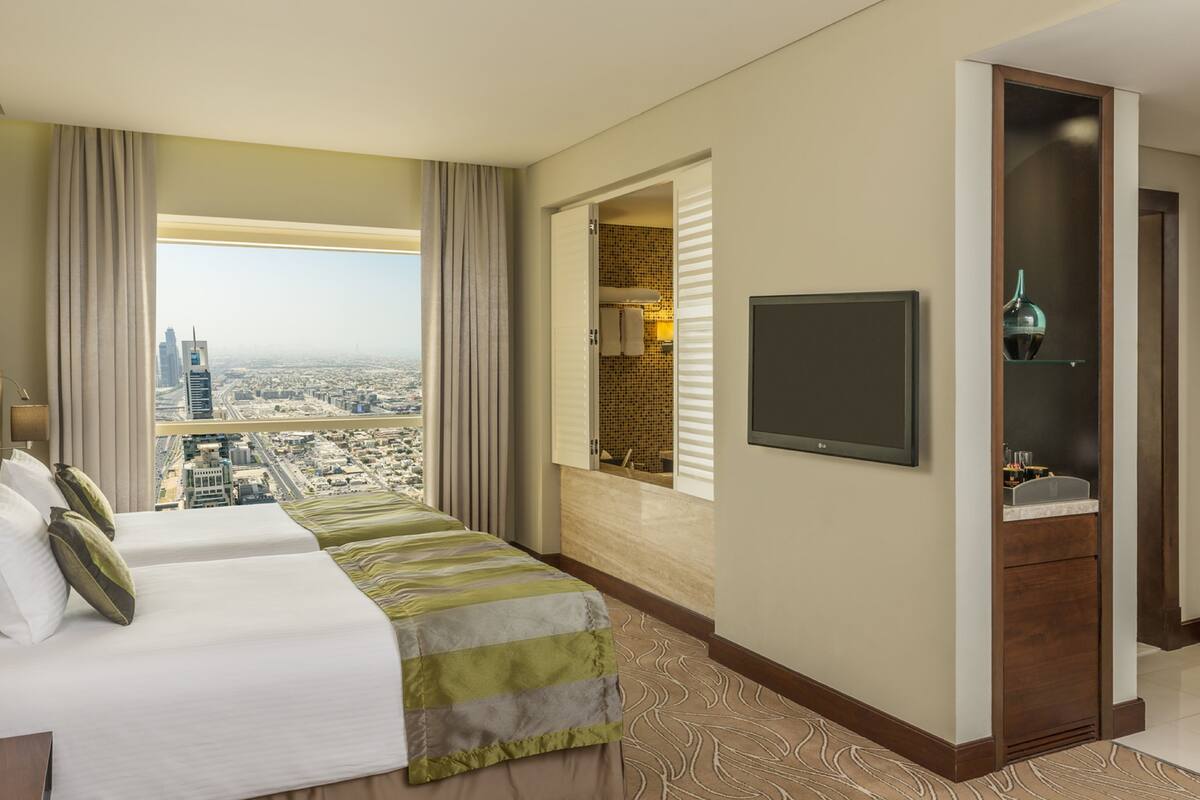 Une chambre d’hôtel avec un grand lit, une télévision et une salle de bain équipée d’un miroir et d’un lavabo.