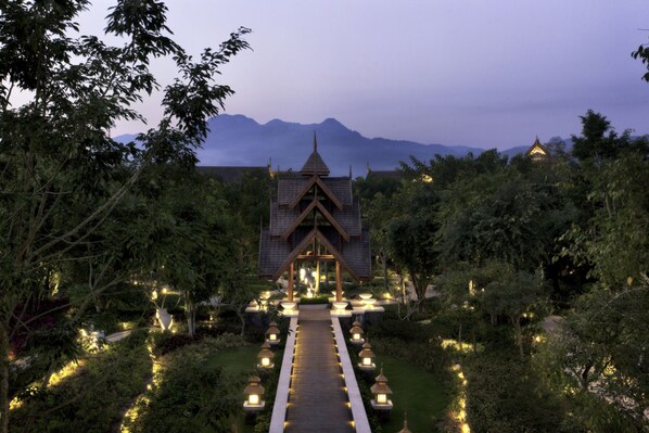 A traditional building with a central pathway leading to it, surrounded by greenery and trees. - Anantara Xishuangbanna Resort (Xishuangbanna Dai)