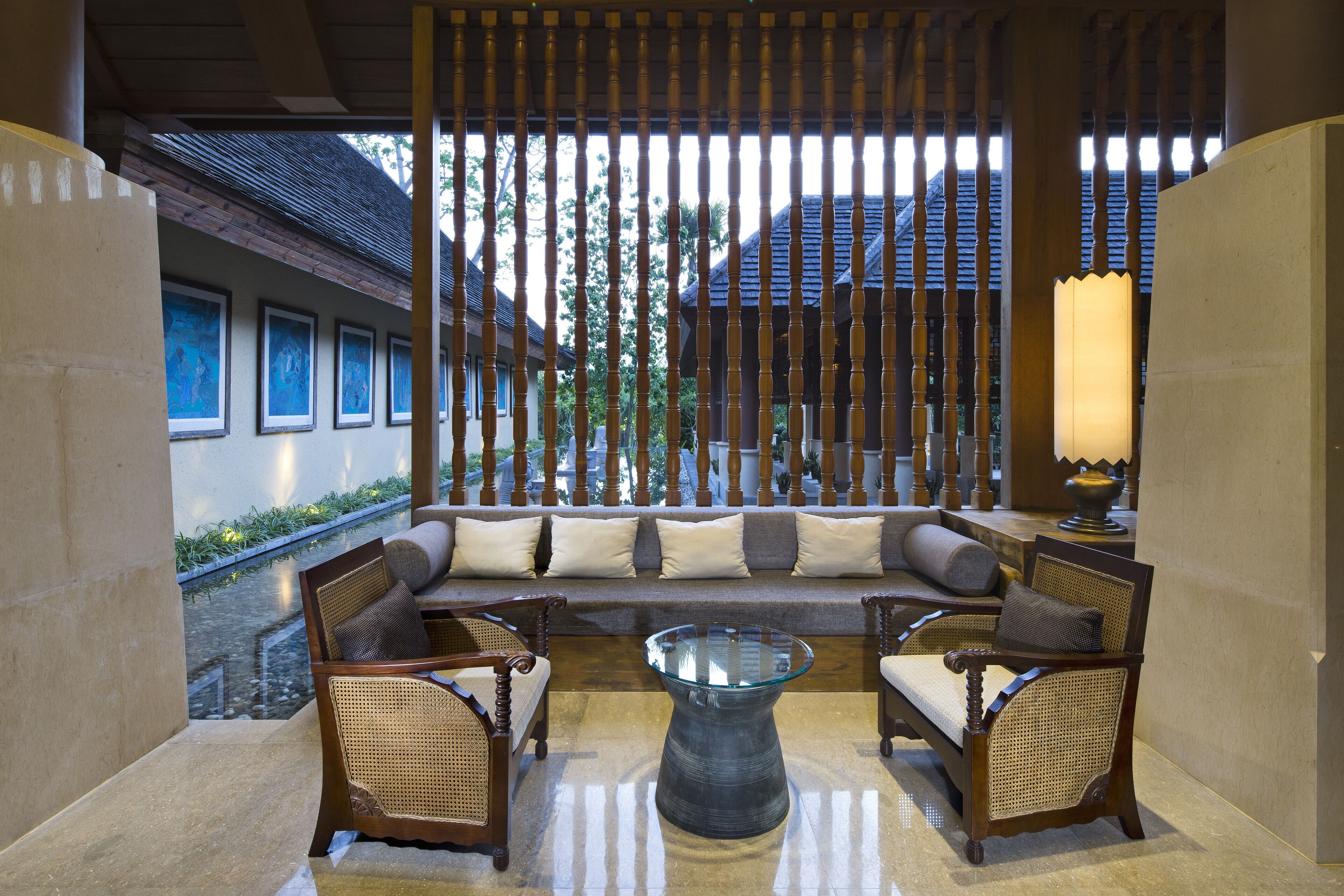 A seating area with a sofa and two chairs, a glass coffee table, and a decorative lamp.