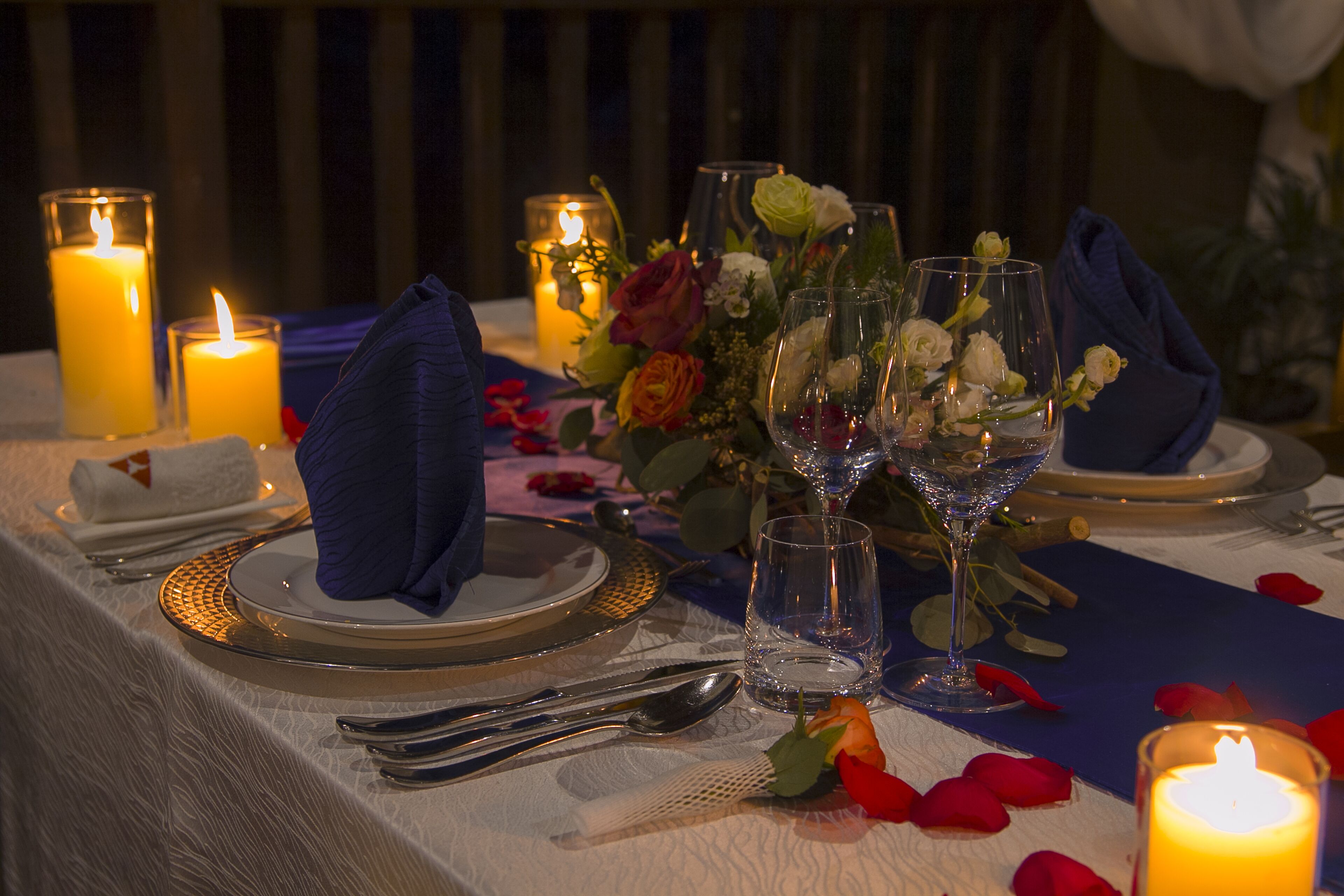 A table set for a meal with candles, glassware, and a floral centerpiece.