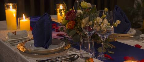 A table set for a meal with candles, glassware, and a floral centerpiece.