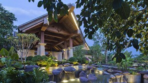 A resort with a large covered pavilion, a landscaped garden with a water feature, and tropical plants. - Anantara Xishuangbanna Resort (Xishuangbanna Dai)