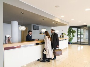 A reception desk with a counter, a television, and a potted plant. - Esperia Palace Hotel (Zafferana Etnea)
