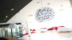 Een modern interieur met hangende, bolvormige kroonluchters en een receptiegedeelte met rode en witte meubels.