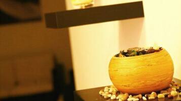 A modern interior with a decorative bowl on a black shelf, surrounded by small objects, and lit candles on shelves.