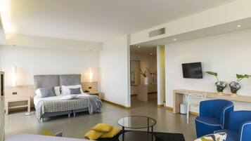 A modern hotel room with a bed, a sofa, a small table, and a TV.