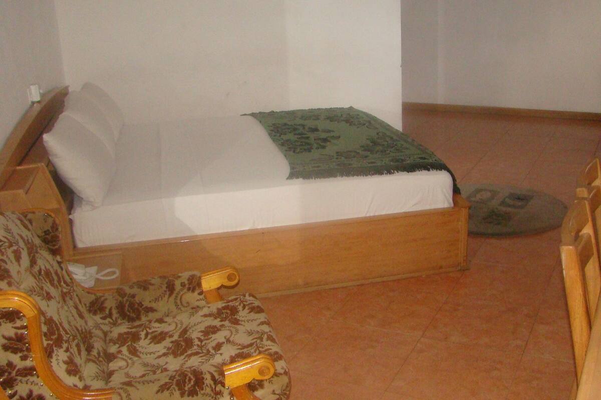 Une petite pièce, de taille modeste, comprenant un lit simple, une chaise en bois et une petite table.